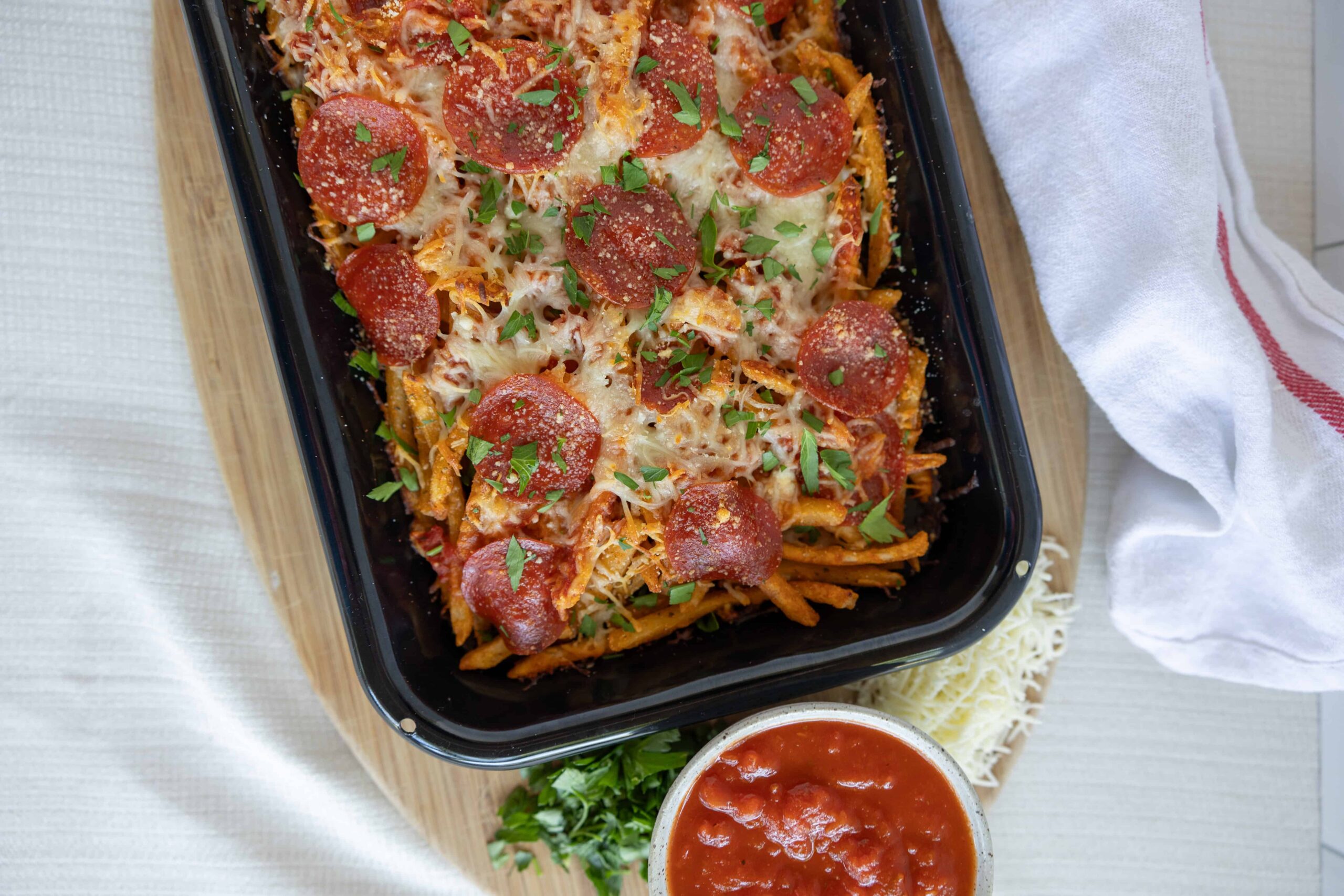 Cheeseburger spaghetti casserole topped with pepperoni and fresh herbs, served with a side of marinara sauce and shredded cheese, ready to bake for a delicious family meal.