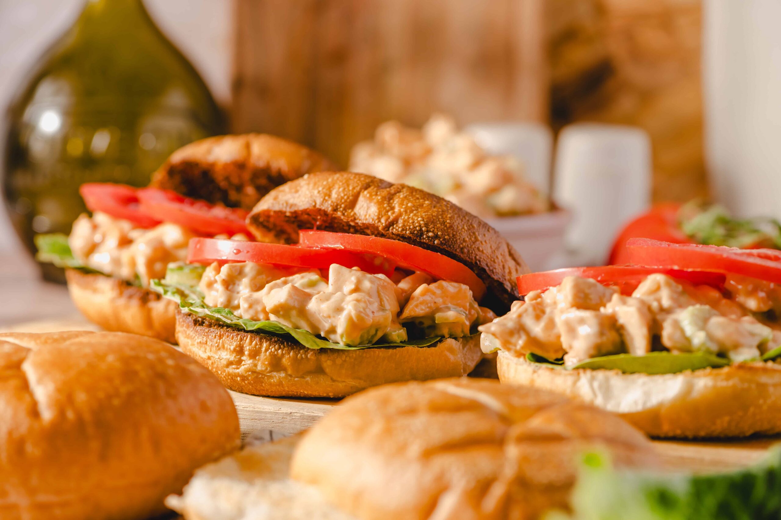 Creamy chicken salad sandwich with fresh lettuce and tomato on toasted bread, served with side bread rolls; ideal for easy lunch recipes and delicious sandwich ideas.