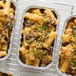 Creamy mushroom and chicken baked pasta in individual aluminum foil containers garnished with fresh parsley. Delicious comfort food perfect for easy weeknight dinners.