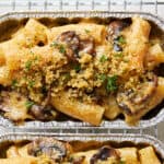 Creamy mushroom and chicken pasta casserole topped with toasted breadcrumbs and fresh herbs, served in aluminum baking dishes for a comforting, hearty meal.