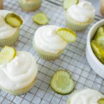 Fresh cucumber and cream cheese cupcakes garnished with cucumber slices on a cooling rack. Perfect for summer snacks or party treats.