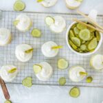 Fresh homemade pickles on a cooling rack with cream cheese and pickle slices, featuring a white and light green color scheme for a tasty snack or appetizer.
