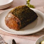 Roast beef with herbs and spices on white plate for dinner or lunch, served with side dishes, gourmet beef dish, seasoned and cooked beef with herbs, holiday meal, tender roast beef.