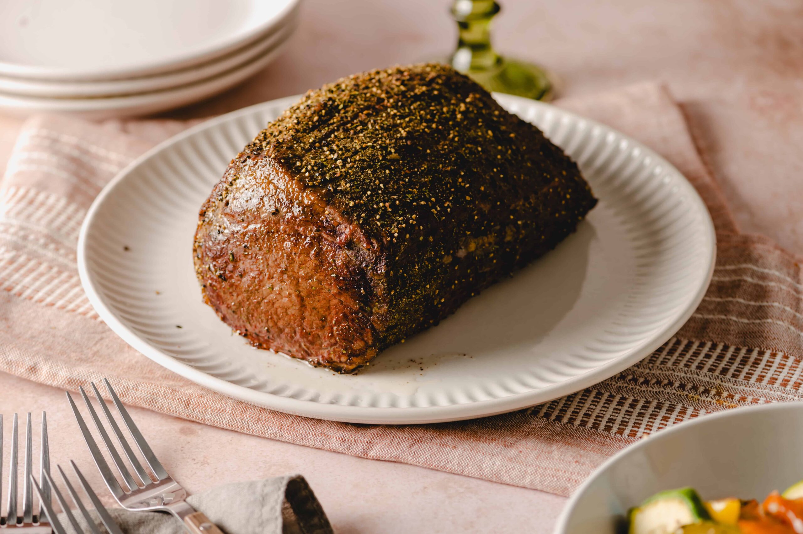 Roast beef with herbs and spices on white plate for dinner or lunch, served with side dishes, gourmet beef dish, seasoned and cooked beef with herbs, holiday meal, tender roast beef.