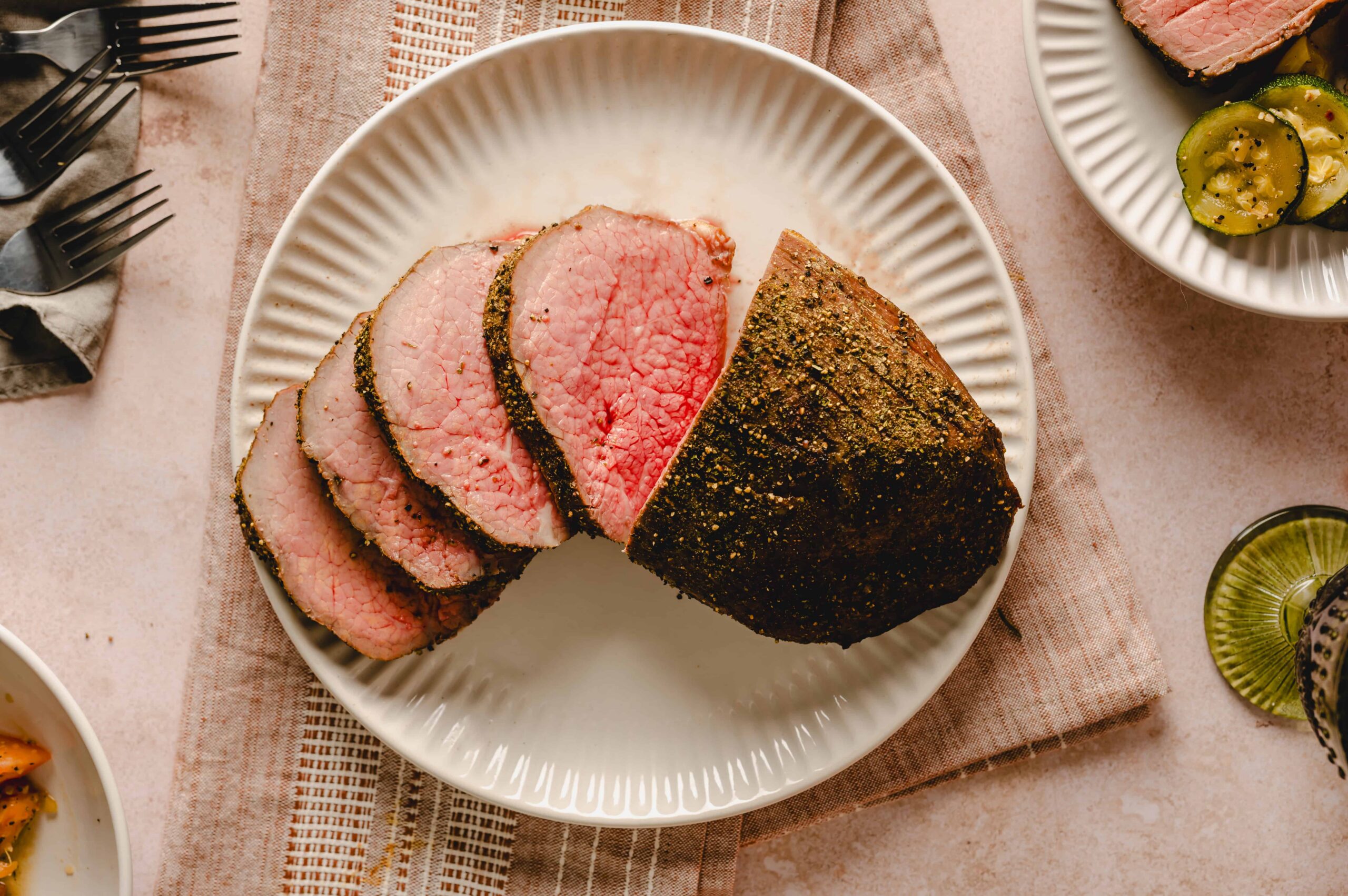 Juicy, perfectly cooked beef tenderloin roast with a flavorful herb crust, sliced and served on a white ceramic plate, ideal for gourmet dinners and special occasions.