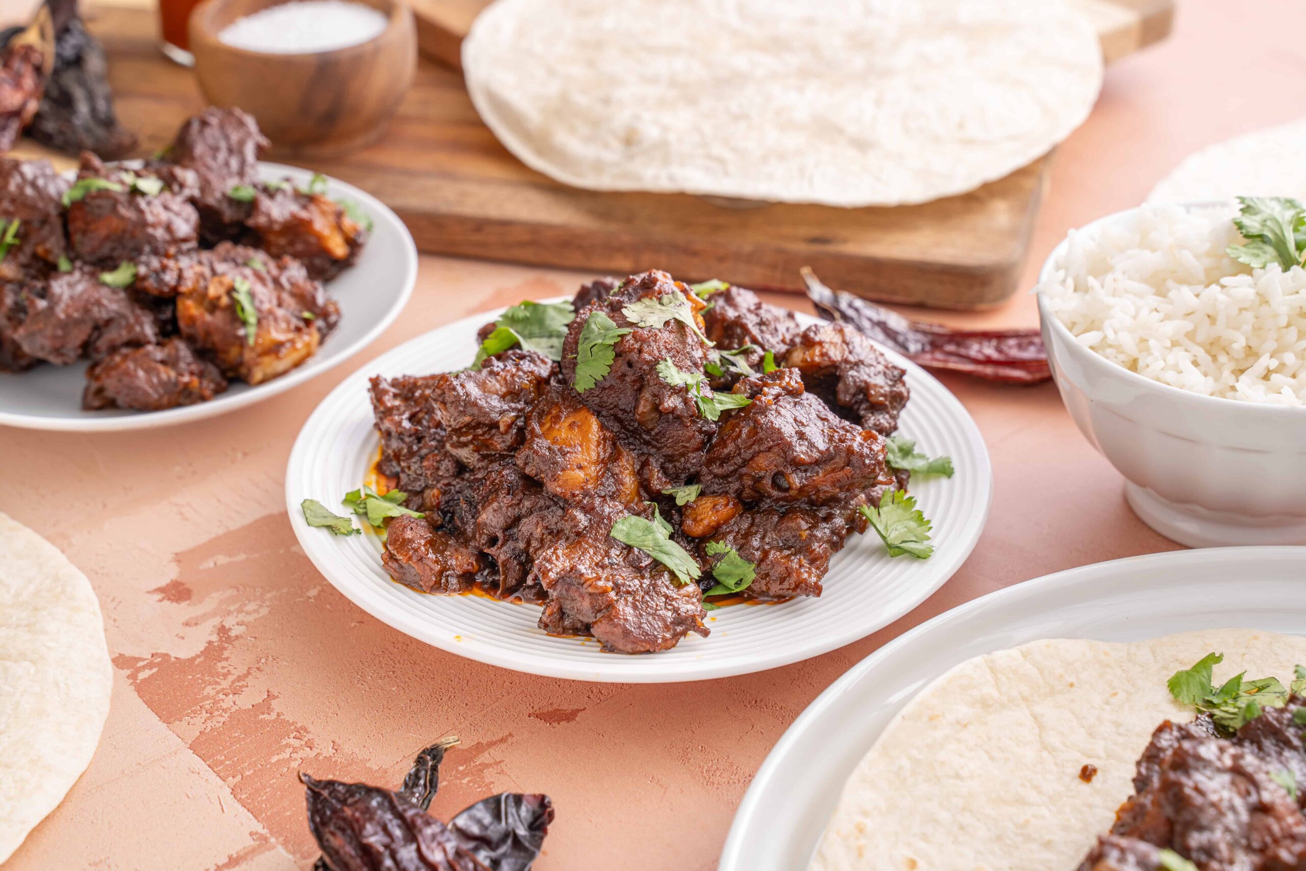 Tender, flavorful beef rendang cooked in rich spices, served with fresh cilantro, alongside rice and traditional flatbread, perfect for an authentic Indonesian meal.