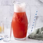 Refreshing watermelon lemonade pitcher with fresh fruit, clear glasses, and colorful straws on a bright kitchen counter.