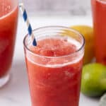 Refreshing strawberry limeade smoothie in a tall glass with a striped straw, featuring vibrant red color and frothy texture, perfect for summer drinks and fruit-based beverages.