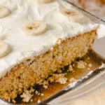 Banana cake with creamy frosting topped with sliced bananas in a glass baking dish. Perfect for banana dessert lovers and easy-to-make banana cake recipes.
