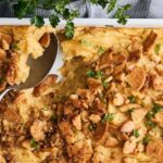 Savory chicken pot pie with flaky crust and golden-brown chicken filling, garnished with fresh herbs, served in a white casserole dish.