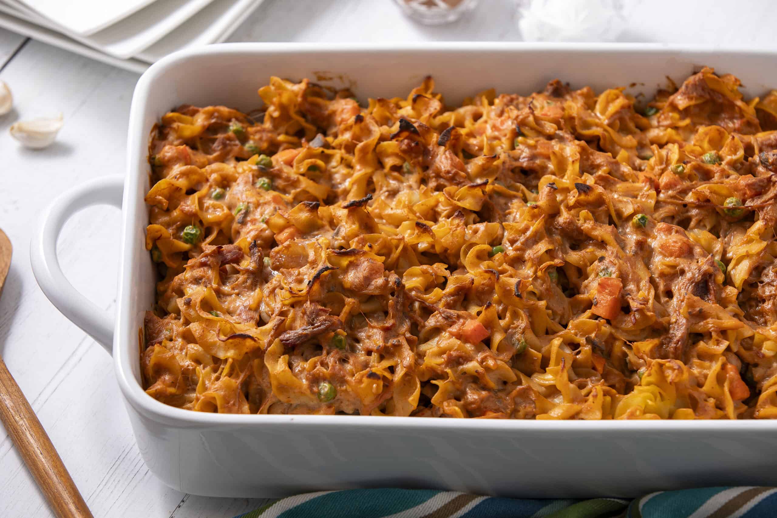 Creamy baked pasta casserole with cheese, vegetables, and meat, served in a white baking dish, perfect for comfort food and family dinner recipes.