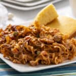 Savory beef stroganoff served with golden cornbread slices on a white plate, garnished with vegetables and creamy sauce, perfect comfort food for dinner or lunch.