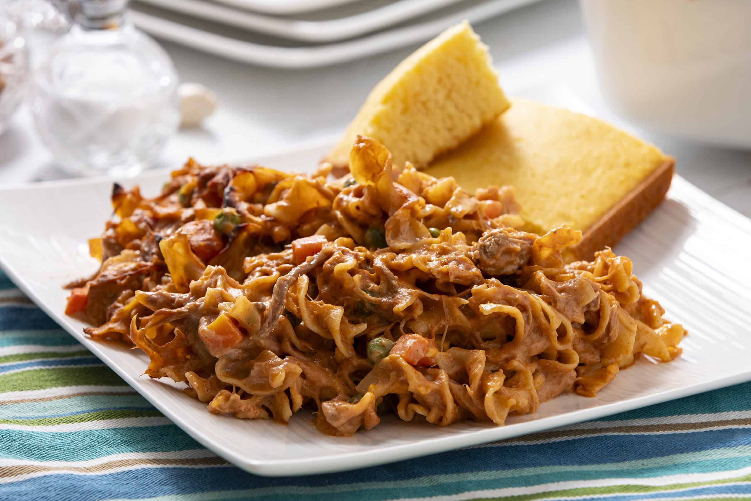 Savory beef stroganoff served with golden cornbread slices on a white plate, garnished with vegetables and creamy sauce, perfect comfort food for dinner or lunch.