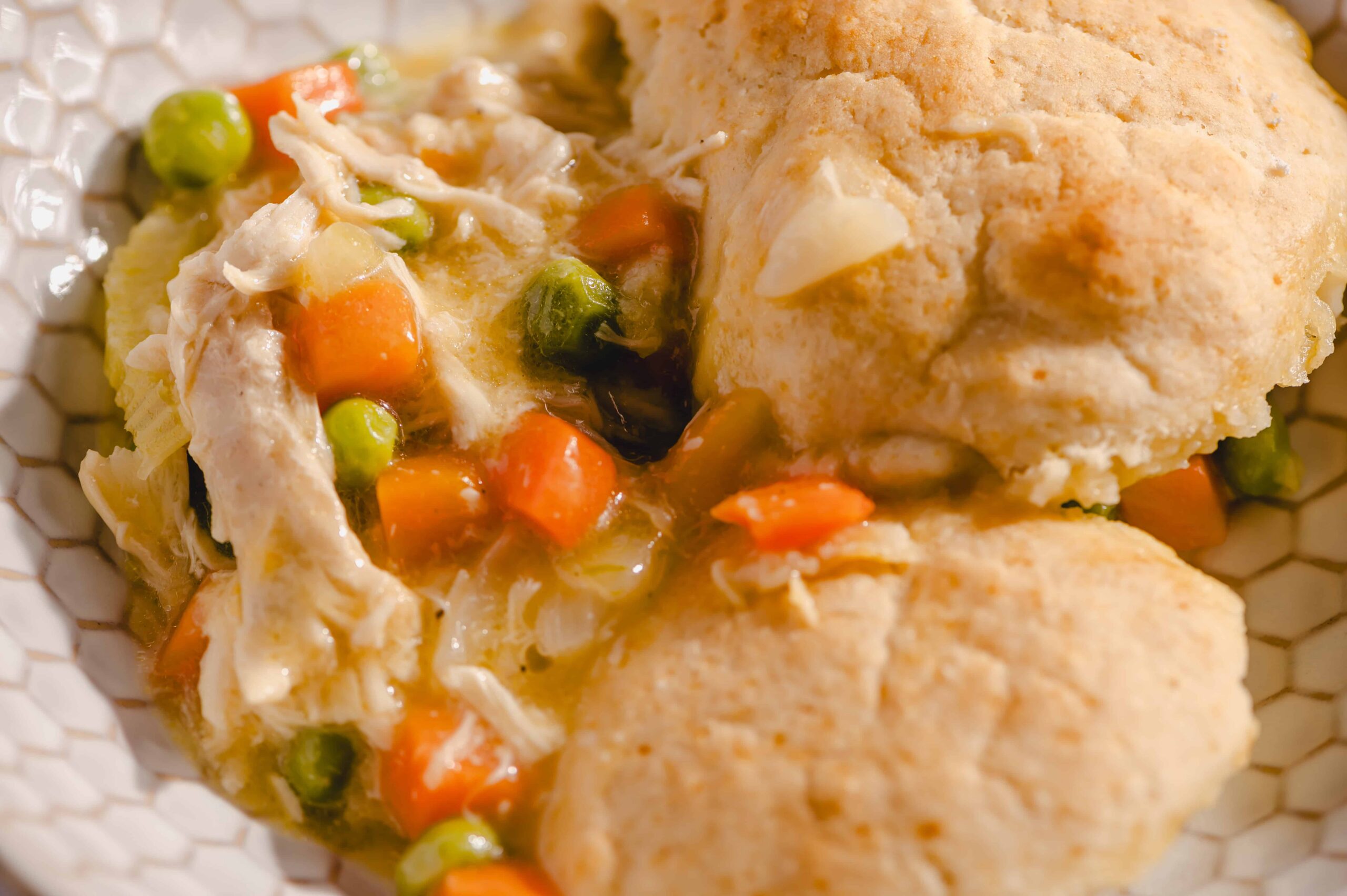 Creamy chicken pot pie with mixed vegetables and flaky golden crust, served hot in a white dish. Perfect comfort food for a cozy meal or family dinner.