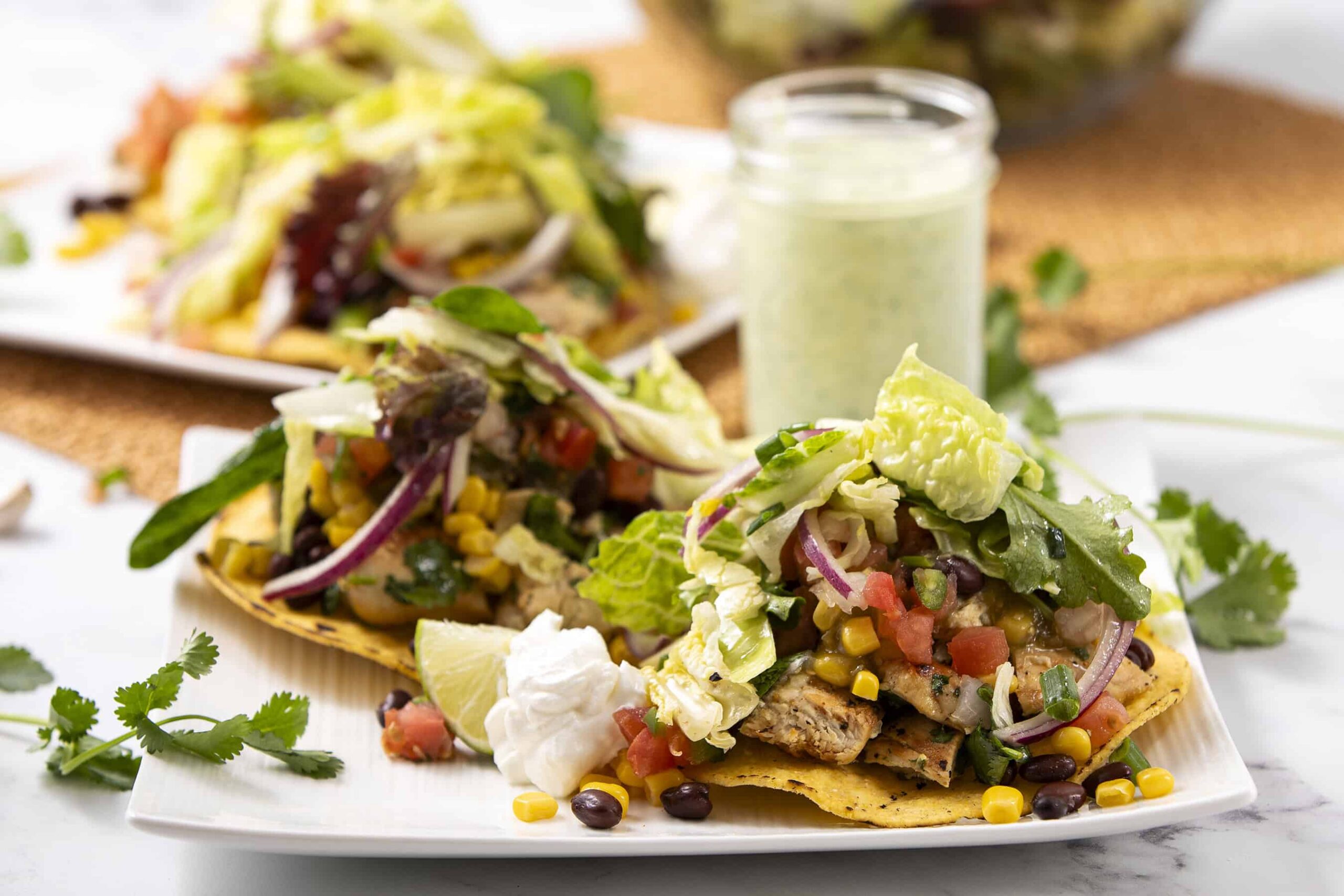 Crispy fish tacos with fresh vegetables, avocado, and lime on a white plate with cilantro garnish and side sauce, delicious healthy seafood recipe, best taco ideas.
