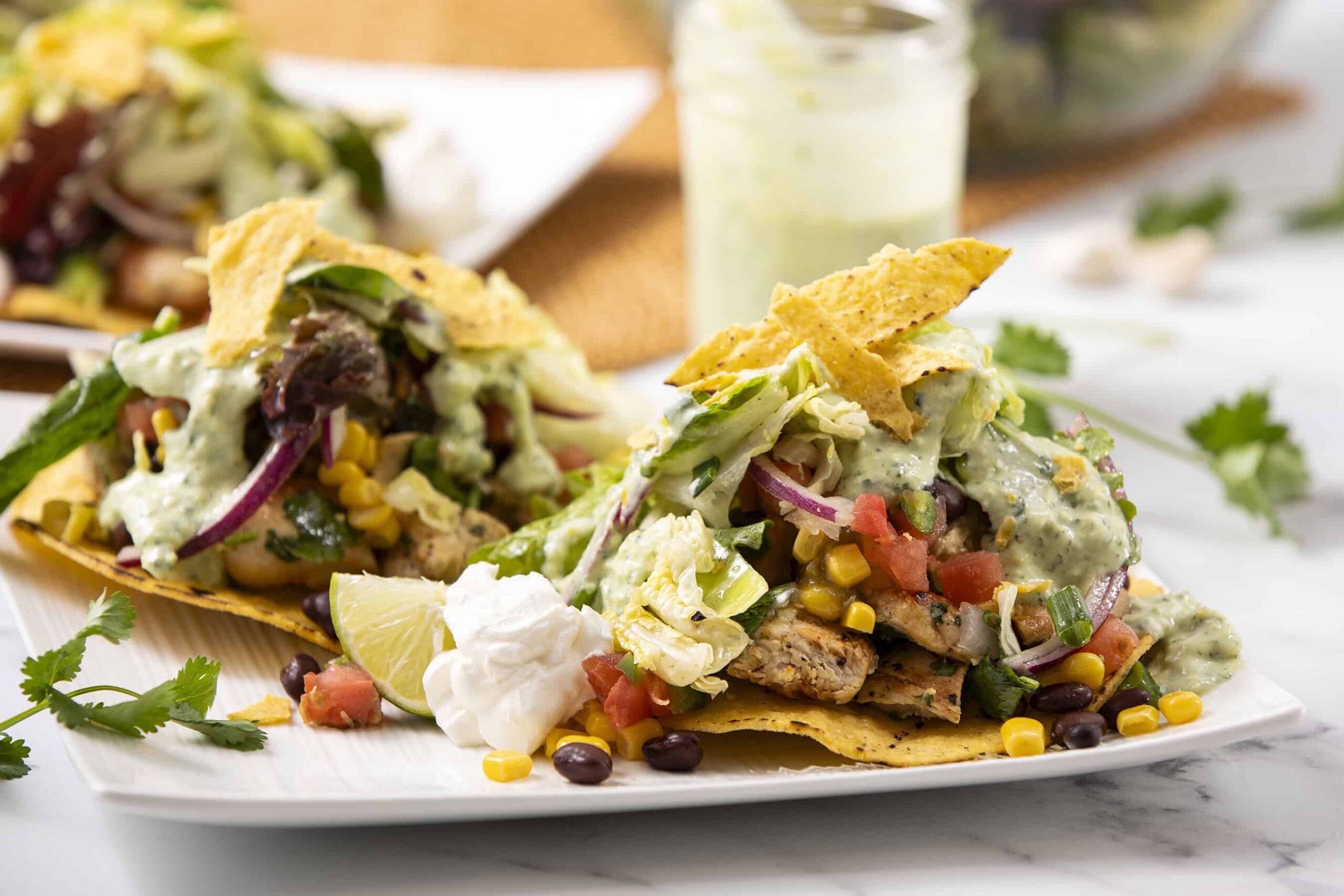 Fresh chicken fajitas with colorful vegetables, creamy guacamole, sour cream, and crispy tortilla chips served on a white plate. Perfect for a delicious Mexican-inspired meal.