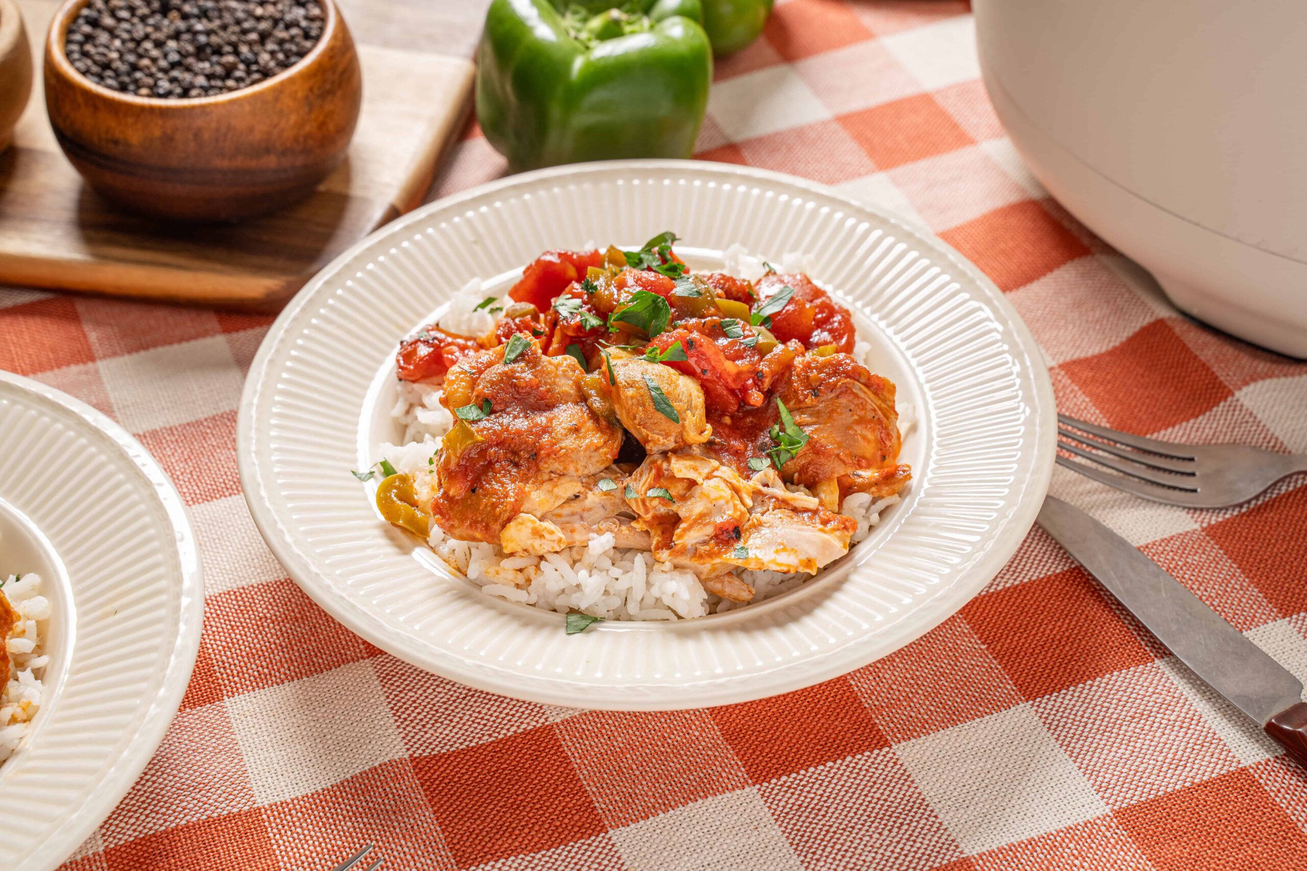Cooked chicken and vegetable stir-fry served over white rice on a beige plate.