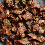 Savory beef stew with tender chunks of beef, mushrooms, and fresh herbs on a black plate for hearty comfort food. Perfect for classic dinner recipes.