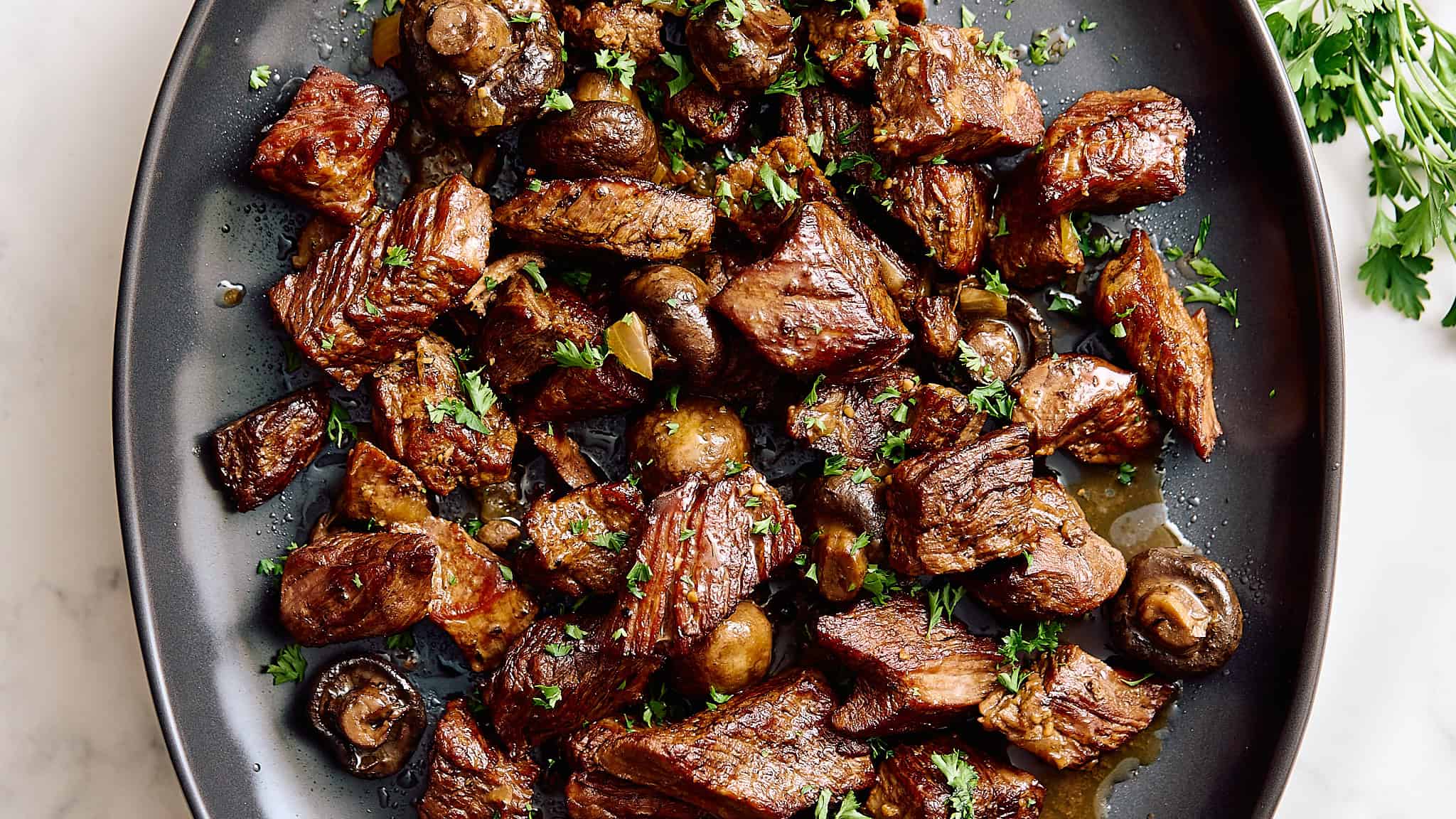 Savory beef stew with tender chunks of beef, mushrooms, and fresh herbs on a black plate for hearty comfort food. Perfect for classic dinner recipes.