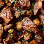 Tender beef stew meat cooked to perfection with mushrooms and herbs, garnished with fresh parsley for a flavorful, savory meal.