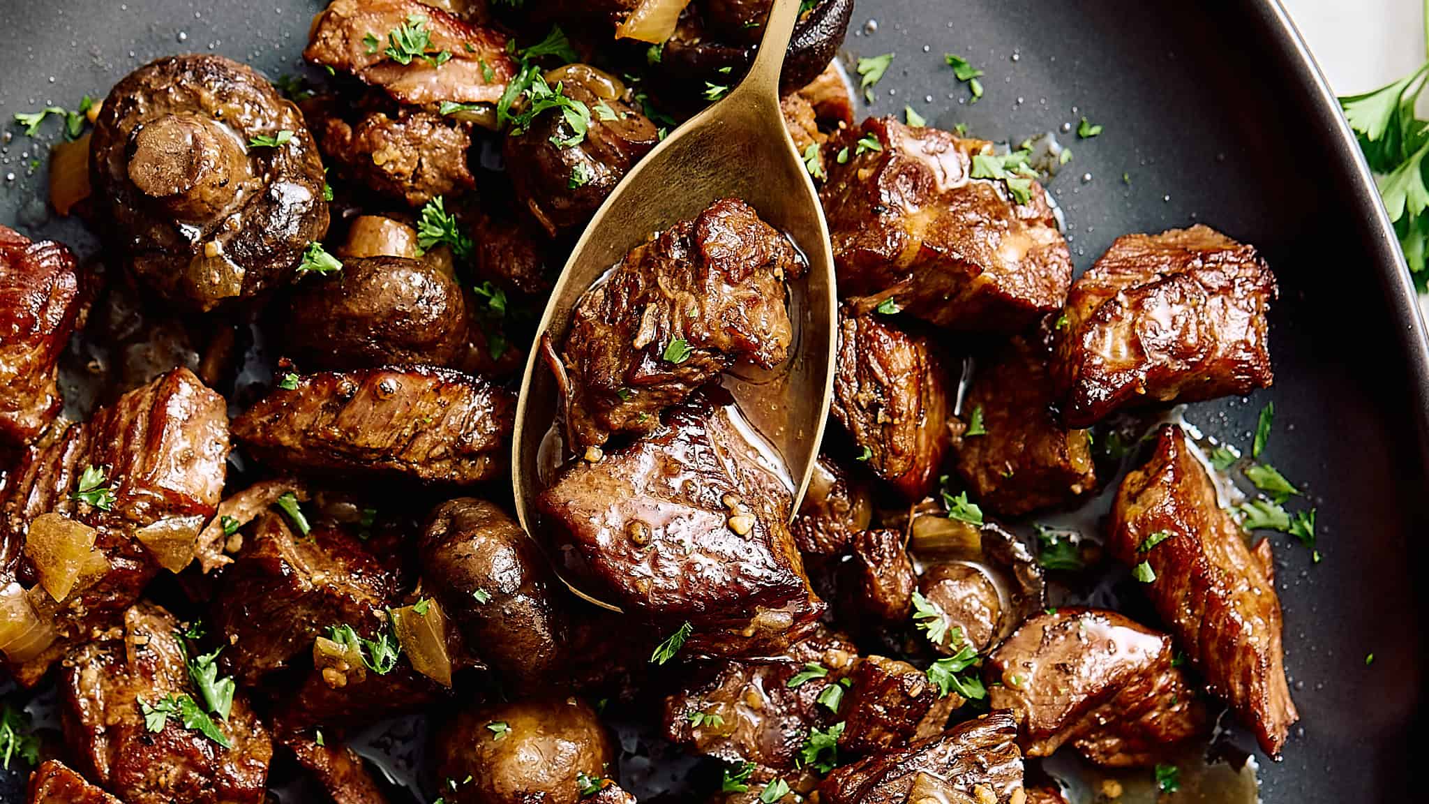 Braised beef stew with mushrooms and herbs in a dark skillet.