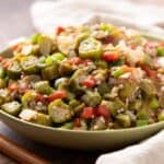 Fresh chopped okra stir-fry with tomatoes and onions in a green bowl, showcasing a healthy and colorful vegetable dish for weeknight dinners and healthy eating.
