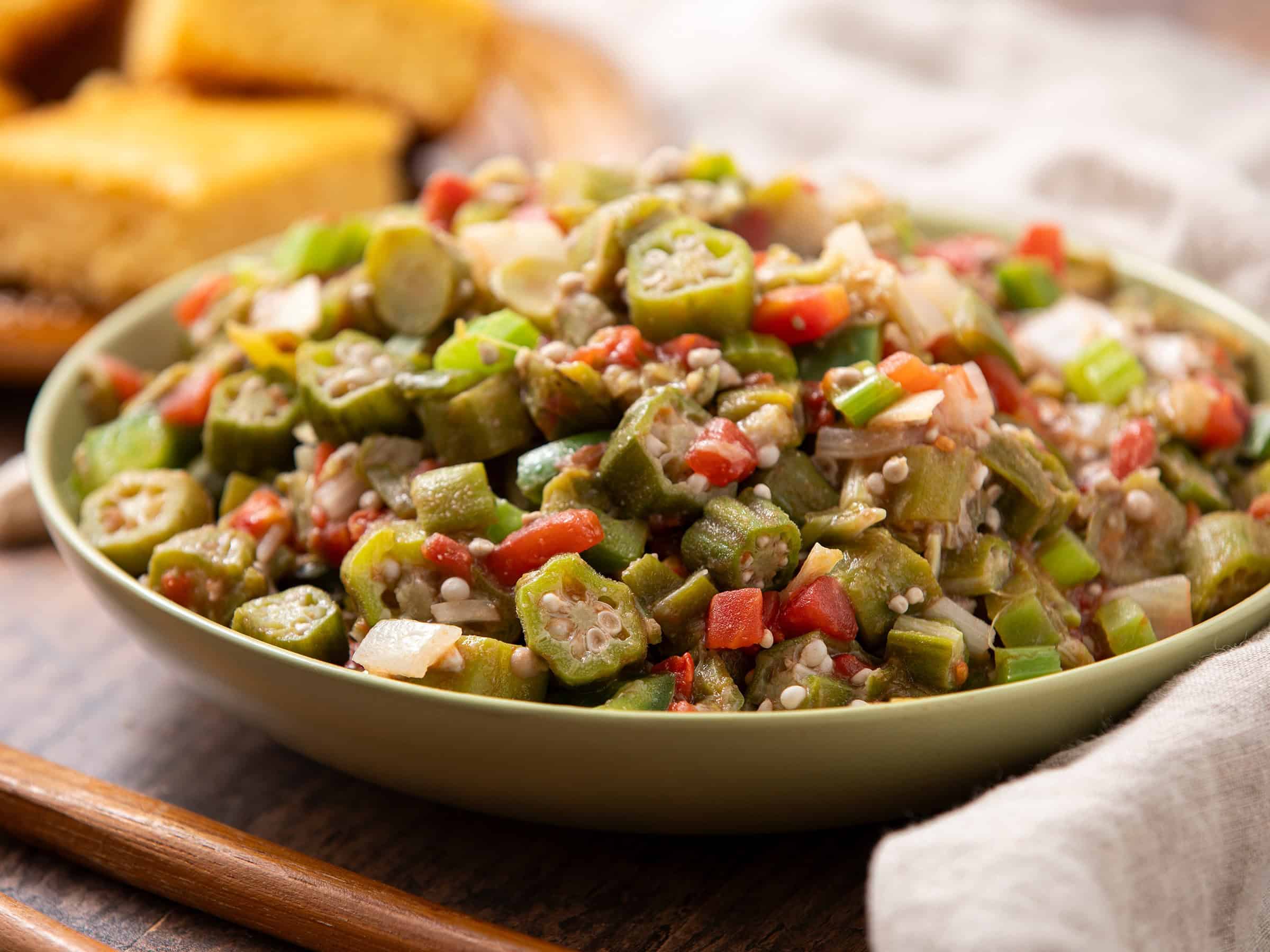 Freshly prepared okra salad with diced vegetables, herbs, and a light seasoning, served in a green bowl. Perfect for healthy, flavorful meals or side dishes during summer or family gatherings.