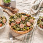 Savory sausage and collard greens on a rustic wooden table, served in white bowls and a wooden plate, ready for a delicious homemade meal with fresh ingredients and comforting flavors.