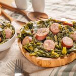 Sausage and collard greens served in wooden and white bowls, fresh ingredients for a hearty Southern comfort food meal.