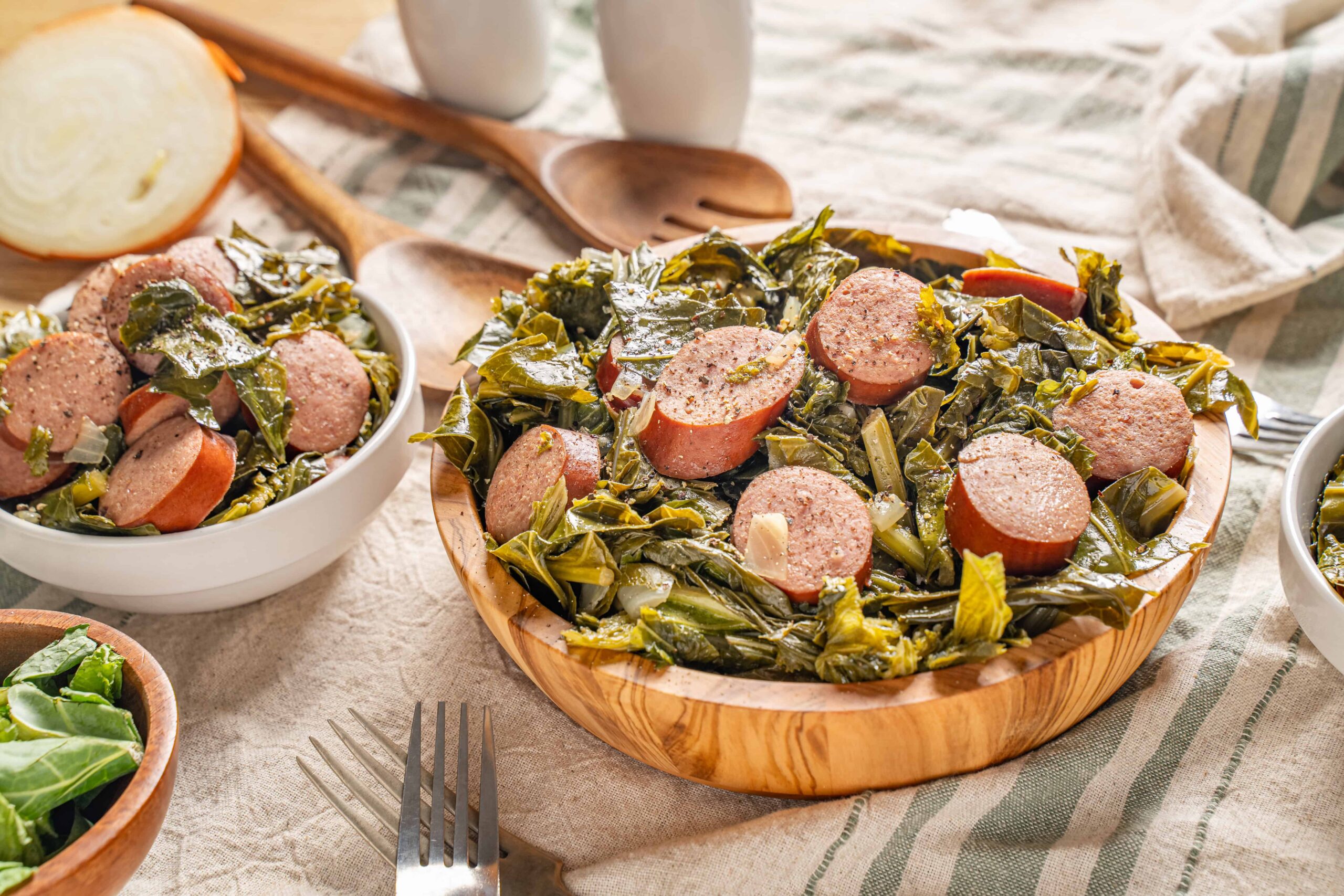 Sausage and collard greens served in wooden and white bowls, fresh ingredients for a hearty Southern comfort food meal.
