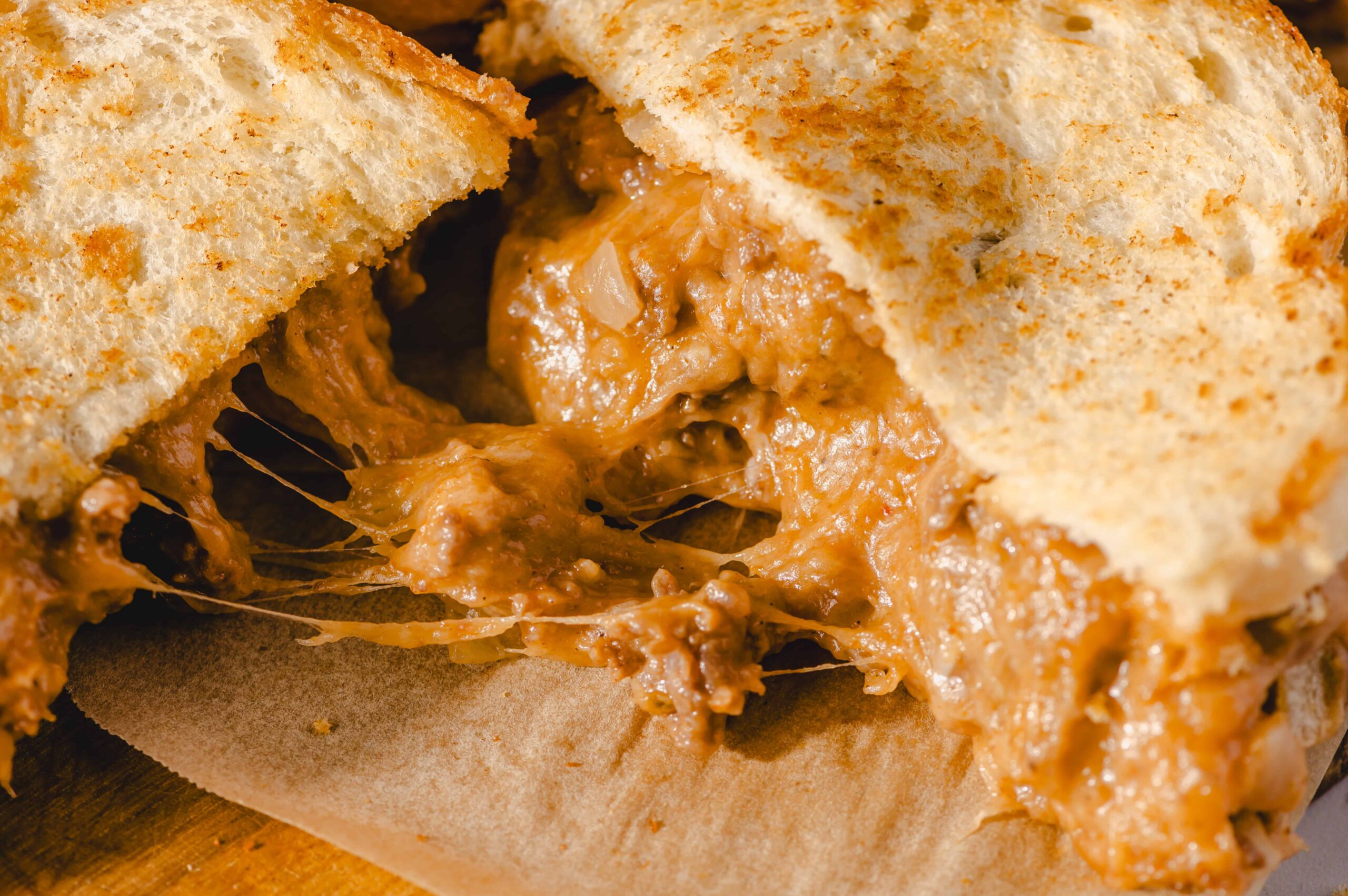 Creamy peanut butter and jelly sandwich with melted cheese oozing out, close-up of a gooey grilled cheese sandwich filled with peanut butter and jelly, delicious comfort food with crispy bread and melting cheese.