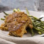 Crispy baked chicken thigh with roasted asparagus on a white plate. Perfect for healthy dinners with flavorful seasonings and tender vegetables. Ideal for meal prep and family-friendly recipes.