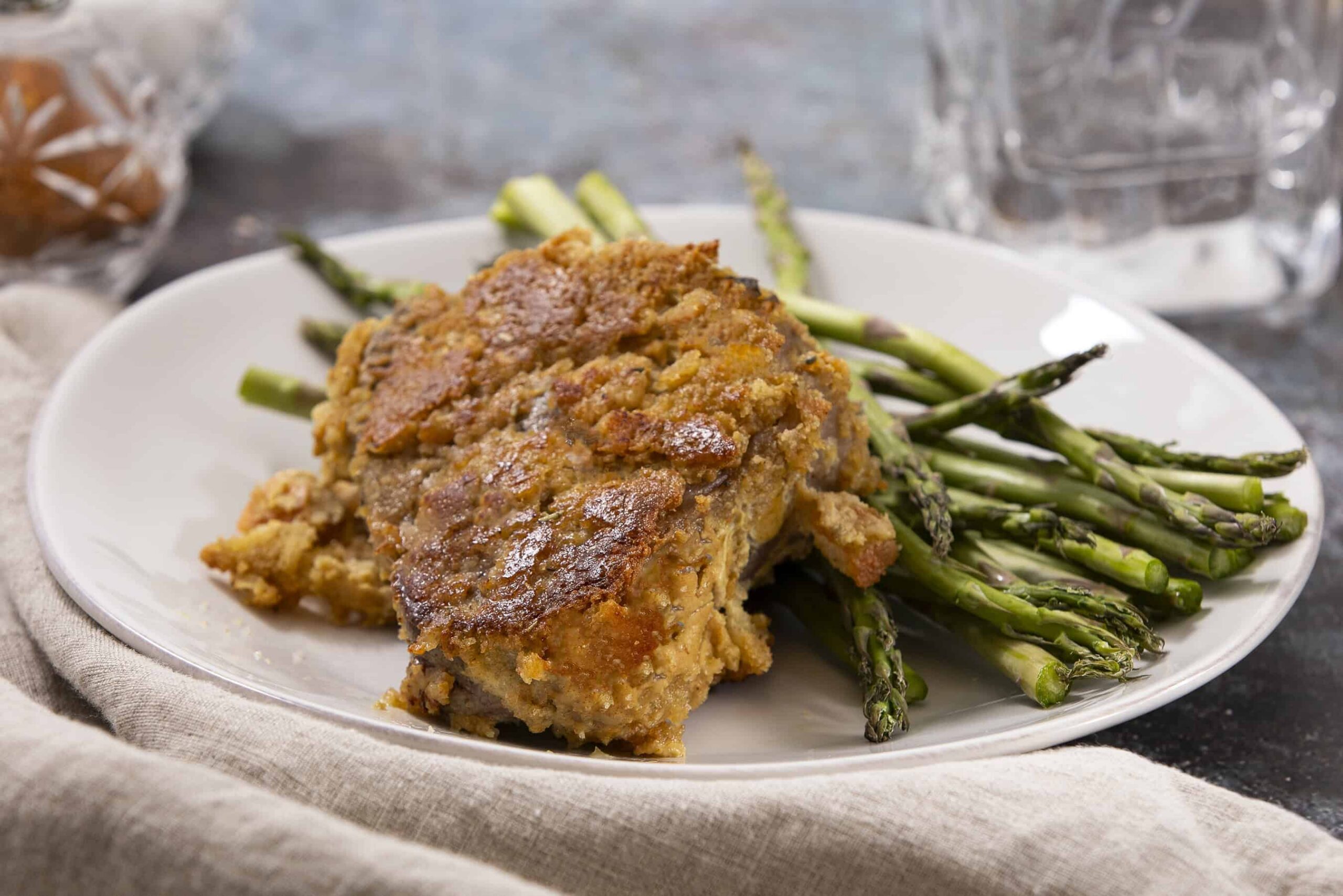 Crispy baked chicken thigh with roasted asparagus on a white plate. Perfect for healthy dinners with flavorful seasonings and tender vegetables. Ideal for meal prep and family-friendly recipes.