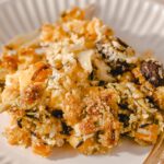 Creamy roasted vegetable casserole with cheese, herbs, and breadcrumbs on a white plate, served with a fork, perfect for vegetarian meal ideas.