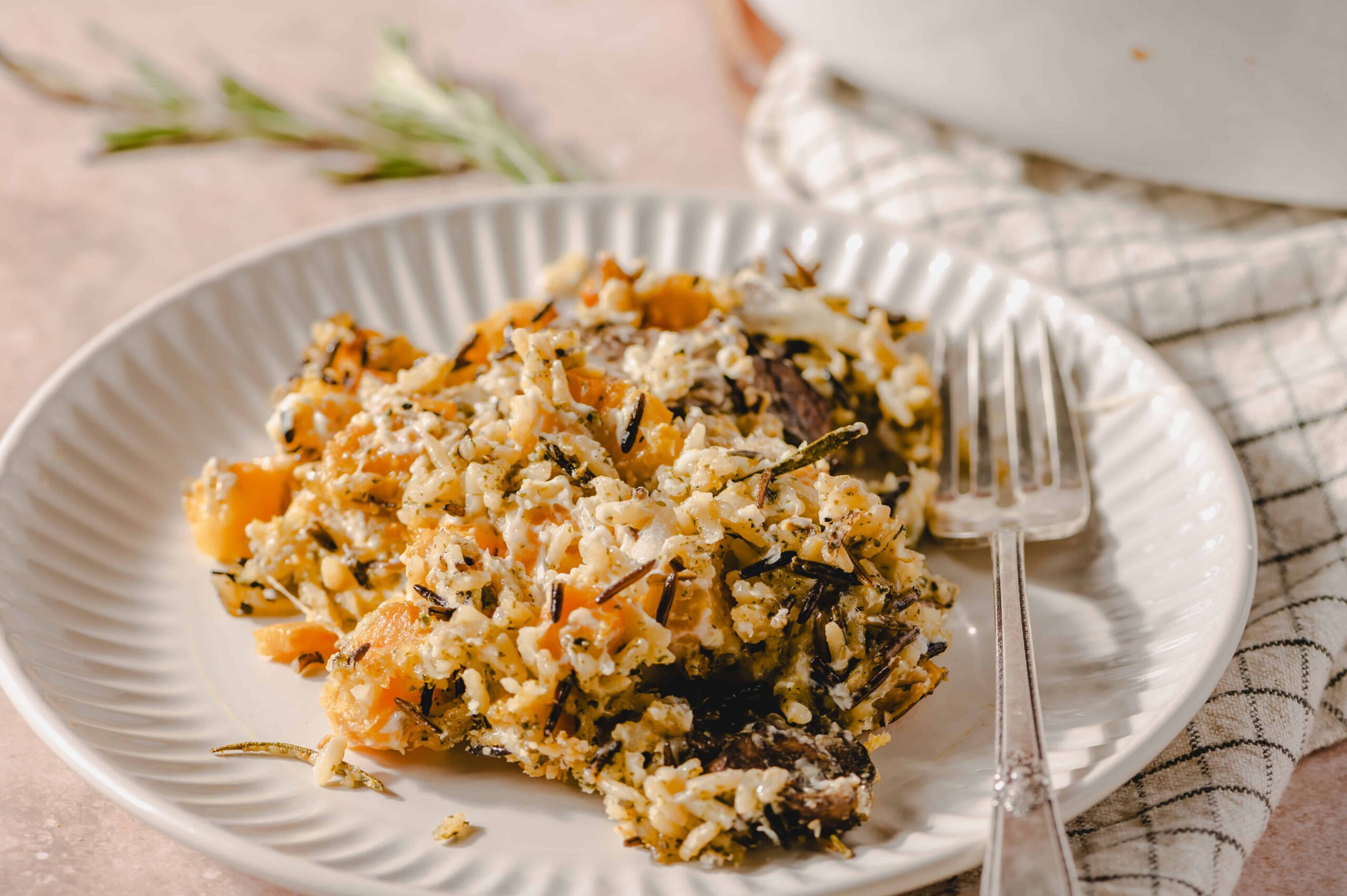Creamy wild mushroom risotto with grated cheese and fresh herbs on a white plate. Perfect comfort food recipe, served with a silver fork on a textured napkin.