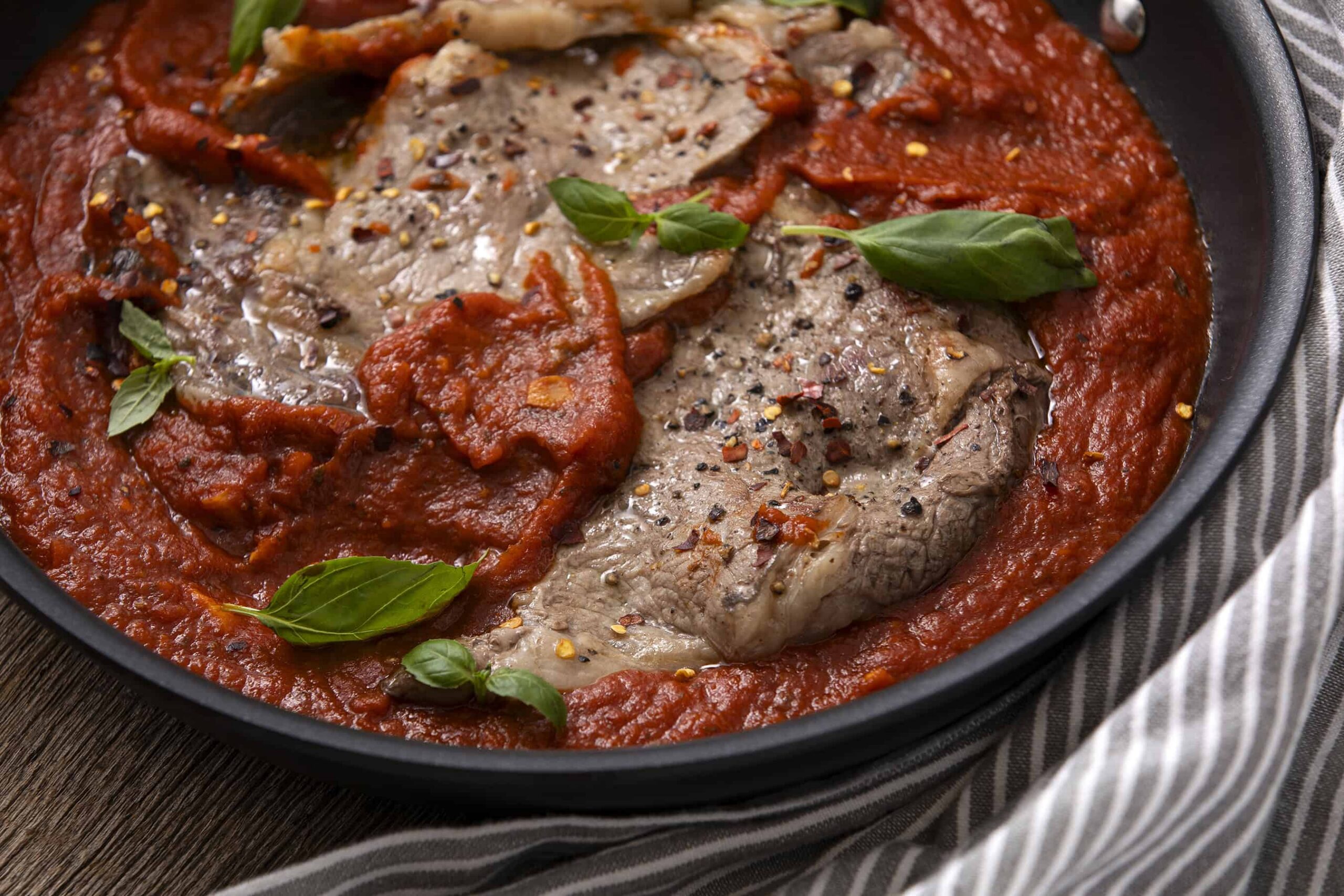 Succulent Italian beef stew with tomatoes, herbs, and spices in a black skillet, ready to serve. Perfect comfort food for hearty dinners.