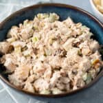 Cold chicken salad with celery and mayonnaise in a blue ceramic bowl, easy healthy summer dish, prepared with shredded cooked chicken, chopped celery, and creamy dressing, perfect for picnics or lunch.