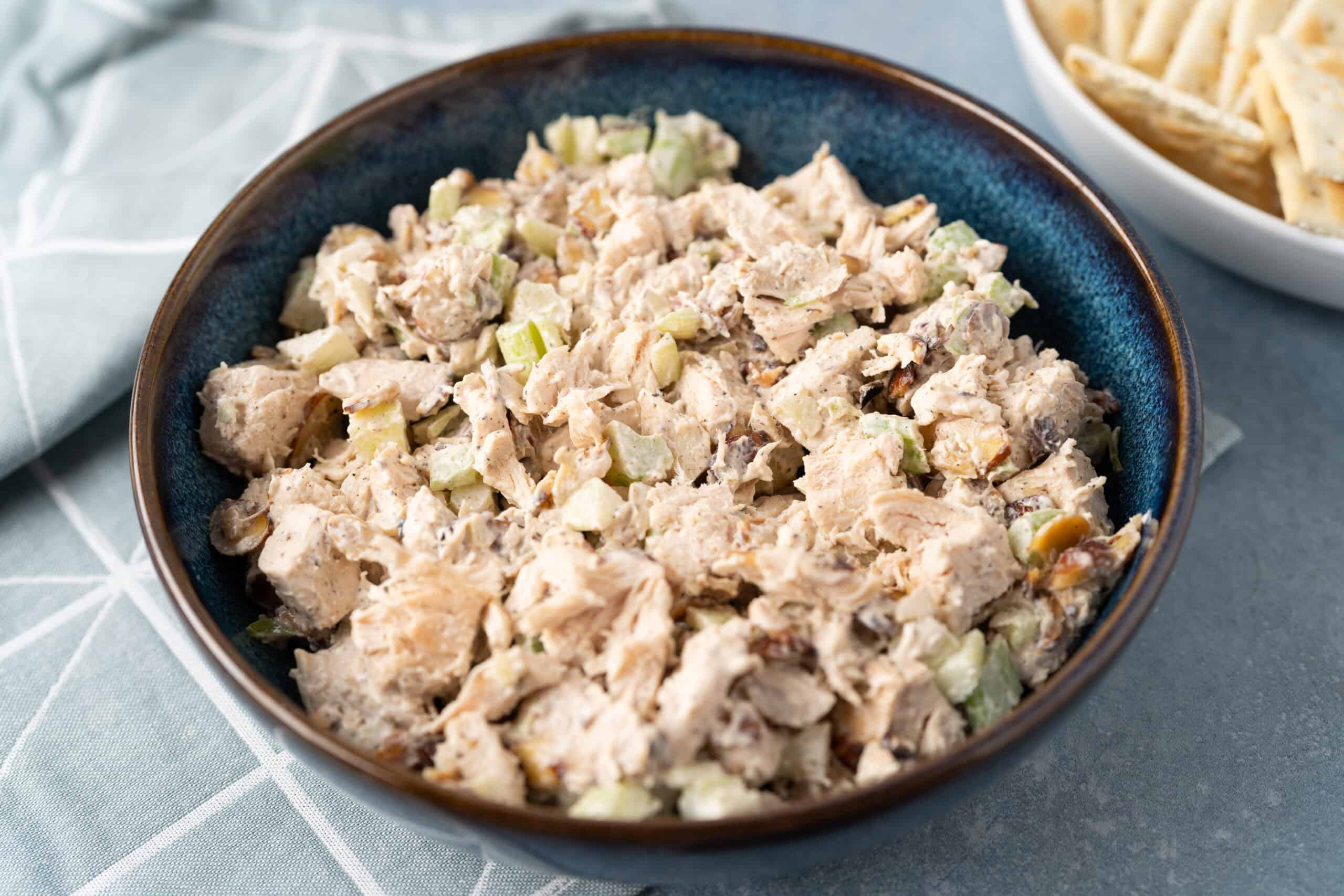 Cold chicken salad with celery and mayonnaise in a blue ceramic bowl, easy healthy summer dish, prepared with shredded cooked chicken, chopped celery, and creamy dressing, perfect for picnics or lunch.