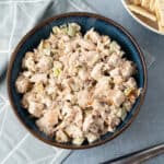 Creamy chicken salad with chopped celery and herbs in a blue ceramic bowl, served as a delicious lunch or appetizer. Perfect for picnics, sandwiches, or light meals. Made with tender cooked chicken and mayonnaise.