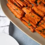 Roasted sweet potatoes seasoned with spices and garnished with herbs, served on a white dish for a healthy, flavorful side dish.