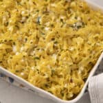 Creamy baked pasta with melted cheese, chopped herbs, and a flavorful sauce, served in a white baking dish for a comforting and delicious meal.
