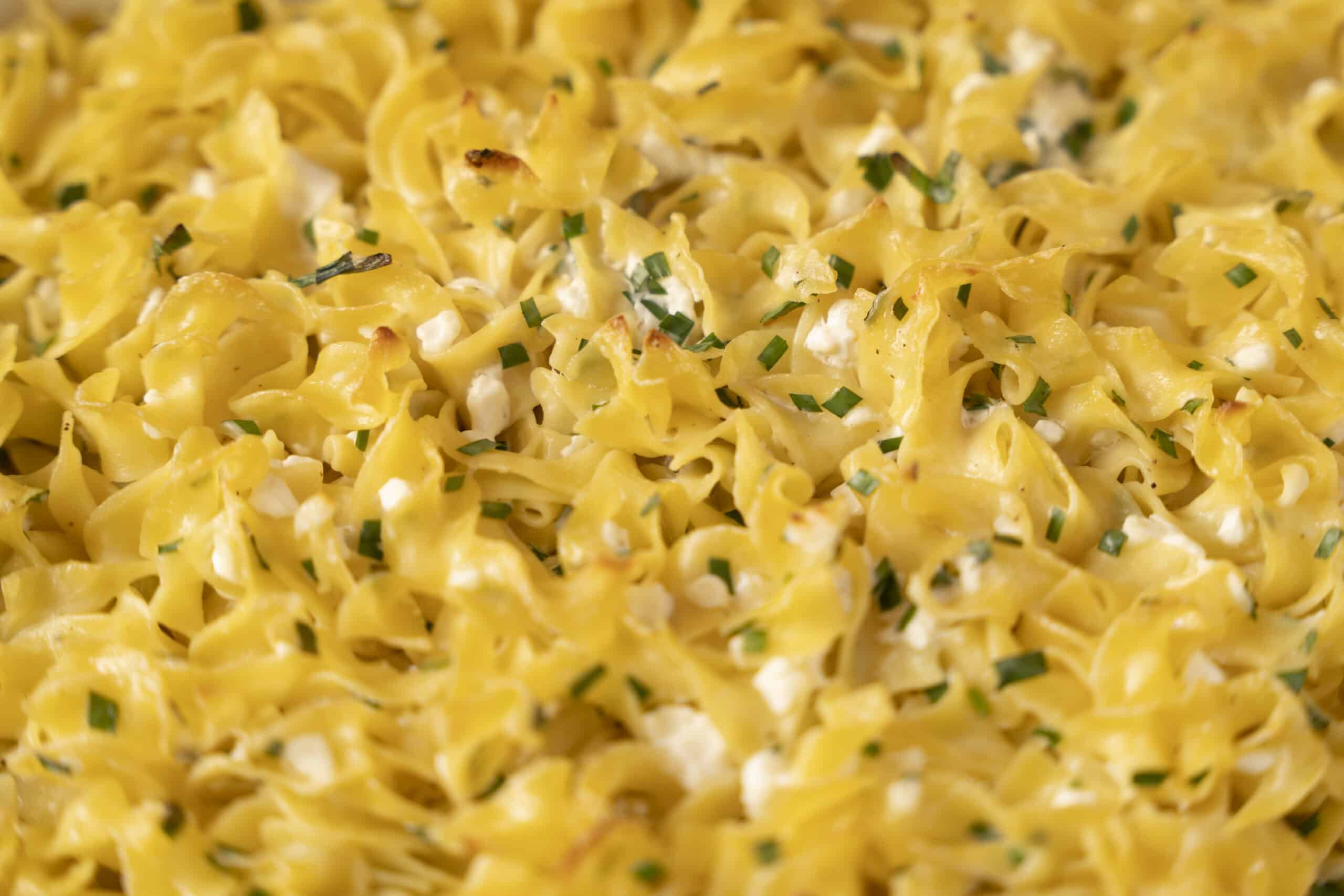 Creamy cheesy pasta with chopped chives, topped with melted cheese and herbs, perfect for comfort food dinners.