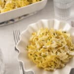 Creamy lemon garlic fettuccine pasta with fresh herbs and cheese, served in a white scalloped bowl for a delicious and elegant meal.