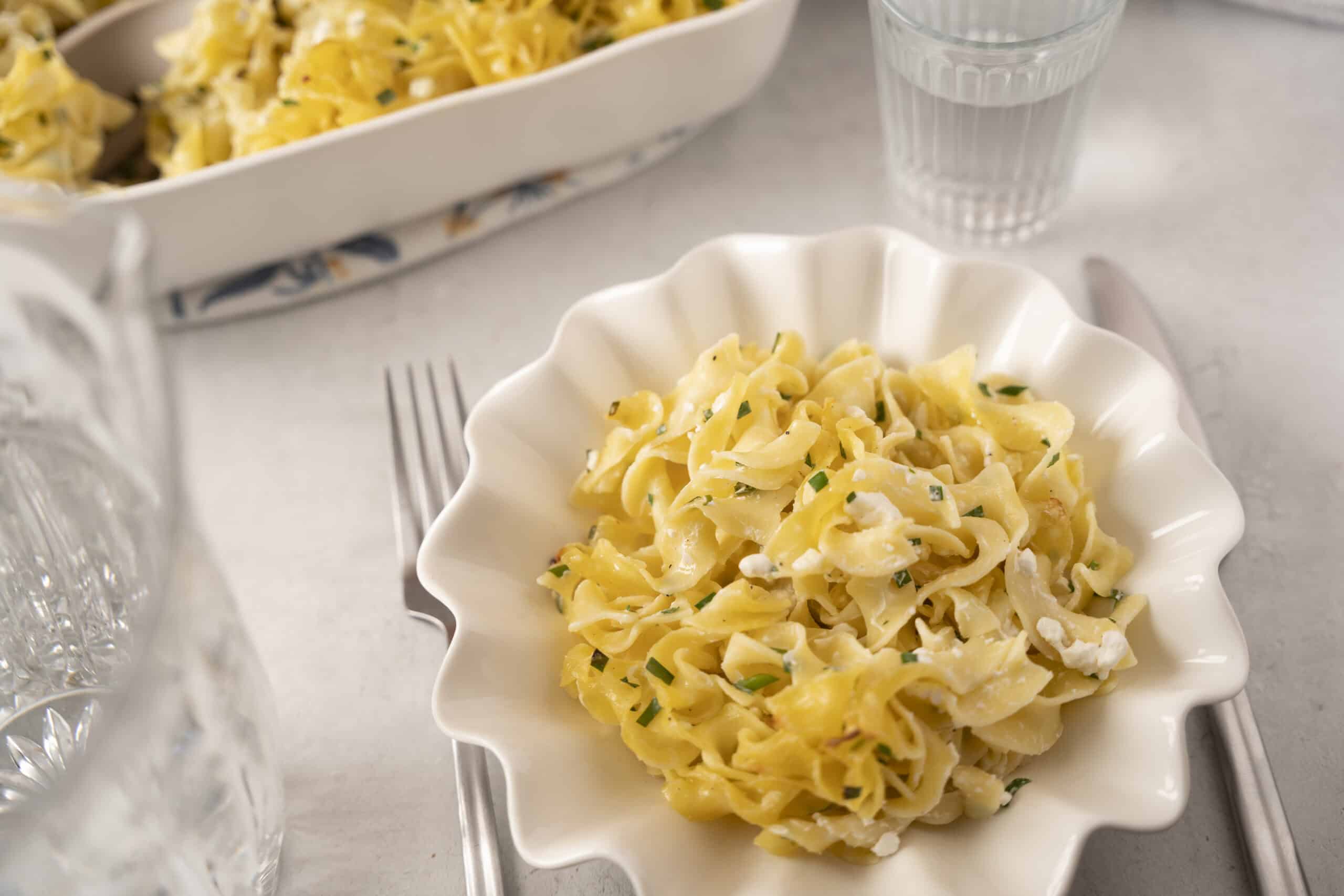 Creamy lemon garlic fettuccine pasta with fresh herbs and cheese, served in a white scalloped bowl for a delicious and elegant meal.