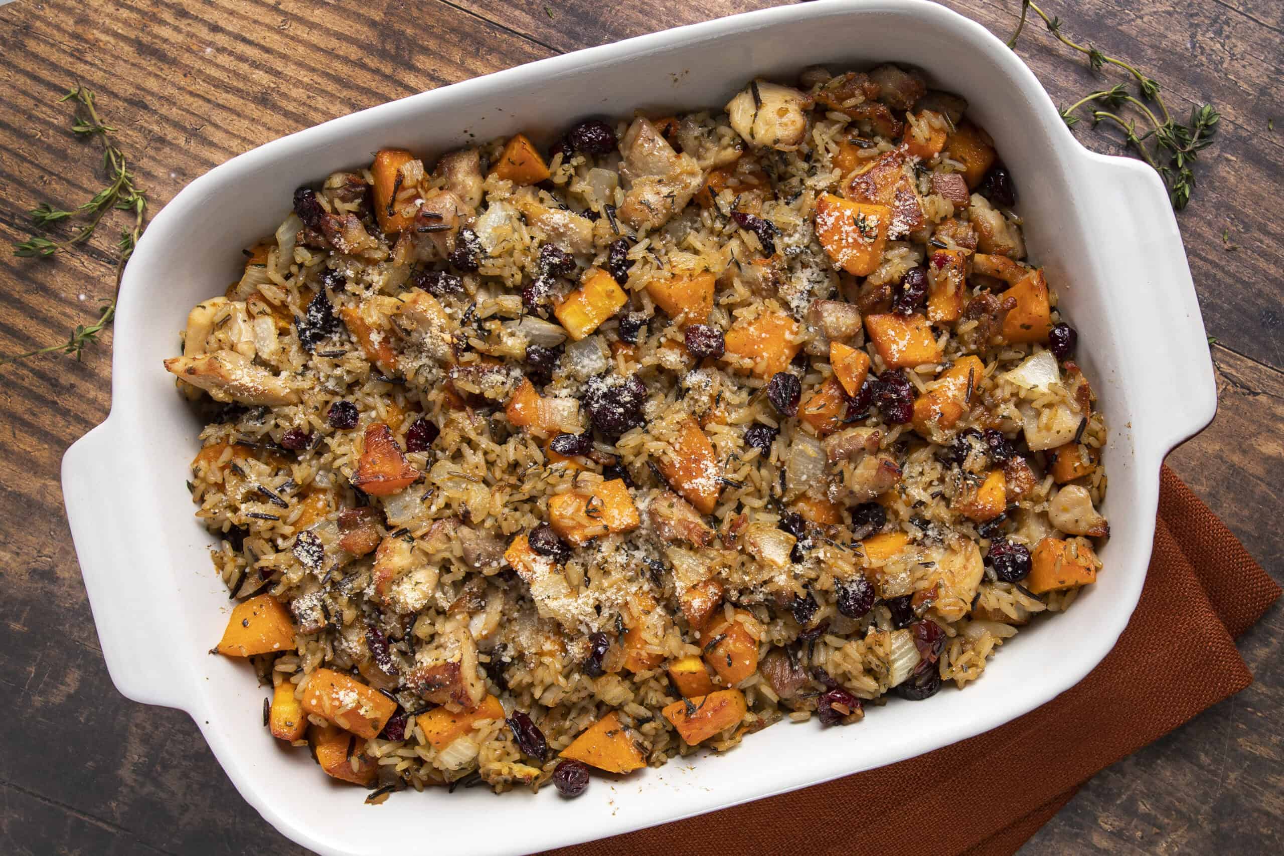 Savory turkey and vegetable rice casserole with sweet potatoes, cranberries, and herbs served in a white baking dish. Perfect for a comforting holiday meal or family dinner.