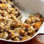 Creamy chicken and rice casserole with sweet potatoes, cranberries, and herbs in a white baking dish, ready for oven baking.