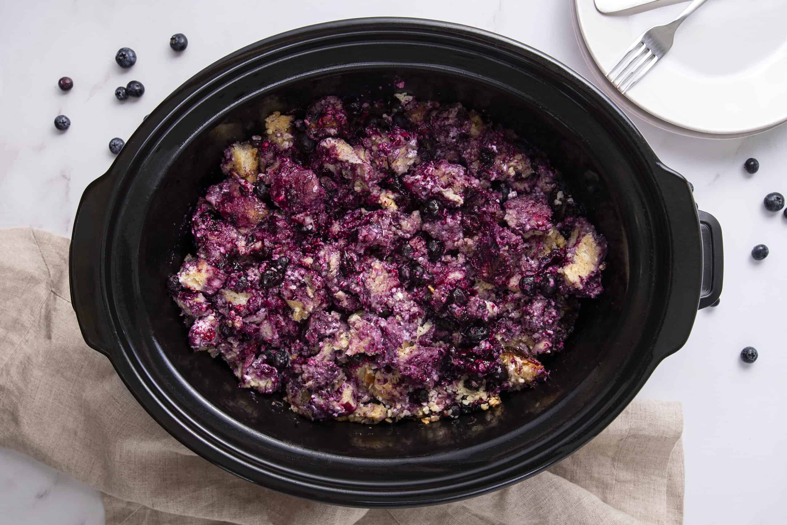 Fresh blueberry cobbler in a slow cooker with a golden brown crust, served as a warm fruit dessert. Perfect for making easy, delicious blueberry cobbler at home with fresh or frozen blueberries.