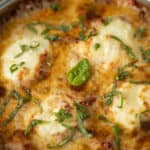 Golden baked lasagna with melted cheese, fresh basil, and chopped herbs, served in a round oven dish. Perfect for family dinners and comfort food lovers.