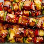 Juicy grilled chicken and vegetable skewers with colorful peppers, onions, and pineapple on a baking sheet. Perfect for summer BBQs and outdoor cooking. Ready to serve as a delicious, healthy meal or appetizer.