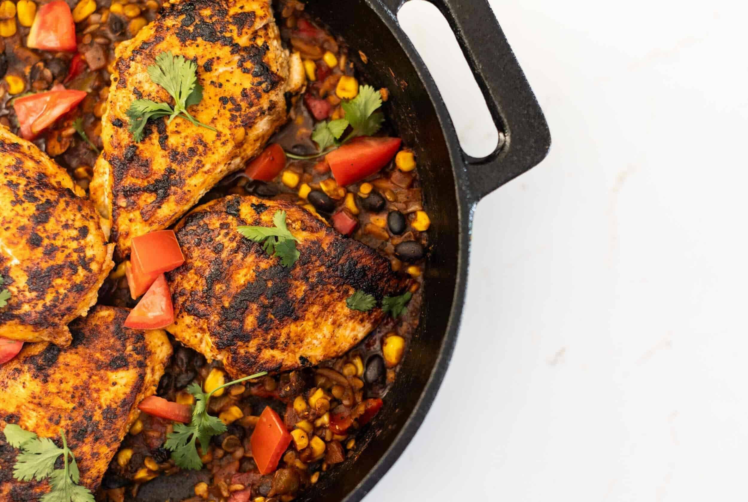 Juicy, flavorful skillet chicken thighs cooked with black beans, corn, tomatoes, and spices in a cast-iron skillet for a delicious, hearty meal.